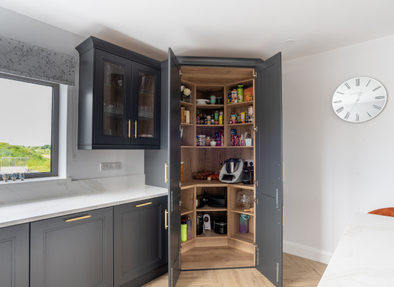 3._Storage Designed Around Modern Family Living Graphite cabinetry paired with gold knurled hardware and Halifax Oak shelving creates a kitchen that feels bold yet balanced throughout the space. Warmer oak textures and metallic detailing soften the darker palette, helping the kitchen feel more inviting and comfortable for everyday living.