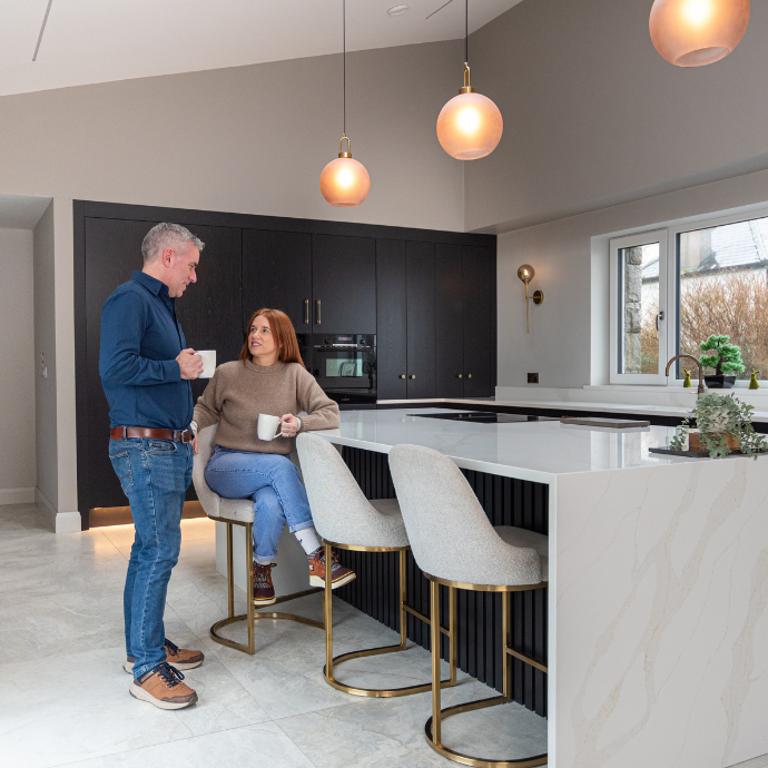 Homeowners in their contemporary MLK kitchen with dark cabinetry and a large stone island